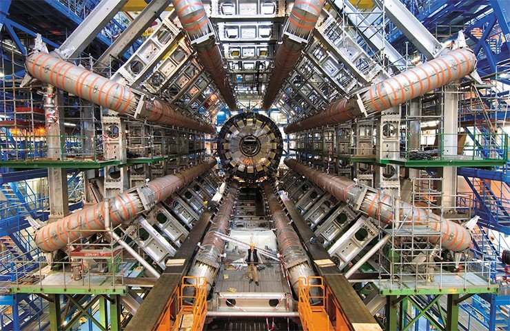 Вид детектора ATLAS с торца в процессе сборки. Восемь расходящихся «лучей» – это сверхпроводящие катушки, создающие тороидальное магнитное поле для искривления траектории частиц и измерения их импульса. На момент снимка калориметры еще не установлены, и центральная часть установки пуста. © CERN