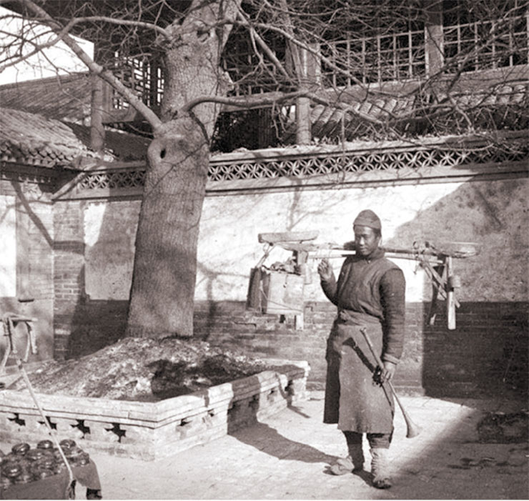 A peddler in the courtyard of a traditional house. Even today, on the streets of some Chinese cities, you can still see people carrying luggage on straight yokes like the one in the photo. 1909. Photo by A. Dutertre