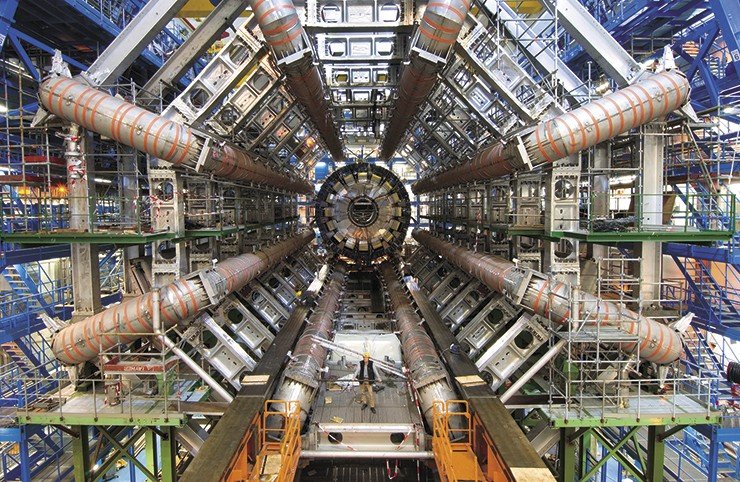 Вид детектора ATLAS с торца в процессе сборки. Восемь расходящихся «лучей» – это сверхпроводящие катушки, создающие тороидальное магнитное поле для искривления траектории частиц и измерения их импульса. На момент снимка калориметры еще не установлены, и центральная часть установки пуста. © CERN