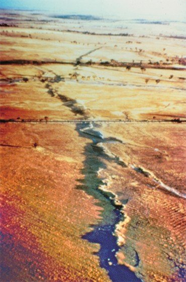 Этот грандиозный разрыв грунта вблизи г. Мекеринг (Австралия) появился 14 октября 1968 г. в результате землетрясения, сопровождавшегося поверхностными волнами. Вид с воздуха. Фото Б. Болта (Архив Калифорнийского университета, Беркли) 