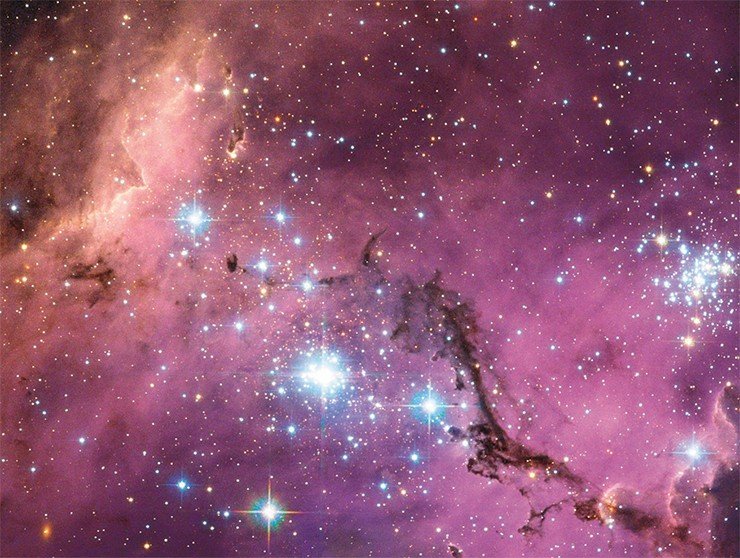 На расстоянии в почти 200 000 световых лет от Земли плывет в долгом и медленном танце спутник Млечного Пути – Большое Магелланово облако. Громадные облака газа внутри него медленно сжимаются, образуя новые звезды. Этот процесс «раскрашивает» облака газа во множество цветов, именно это мы видим на снимке. Image Credit: ESA/NASA/Hubble