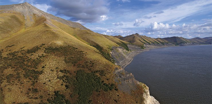 Tas-Ary Island is situated opposite a left tributary of the Bulkur River. Slightly south of the place, two rivers join the Lena: the Khatystakh and the Ulakhan-Aldyrkhai. A contact between sedimentary rocks of the Cambrian (light) and Permian (dark) Systems is apparent in exposures