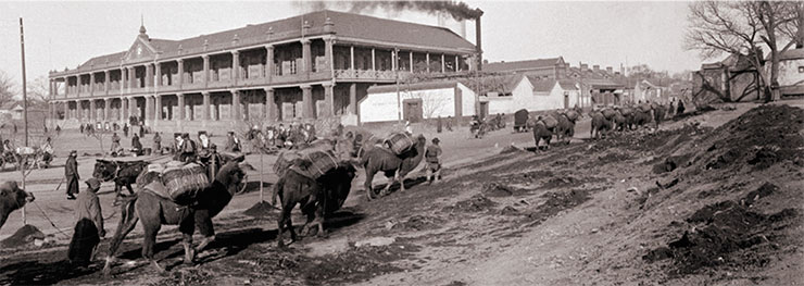 As if along the Silk Road, a pack caravan enters Wangfujing and walks past the administration of the Beijing–Haikou Railway. The white-walled structure next to the headquarters was the one where foreign engineers lived. 1909. Photo by A. Dutertre