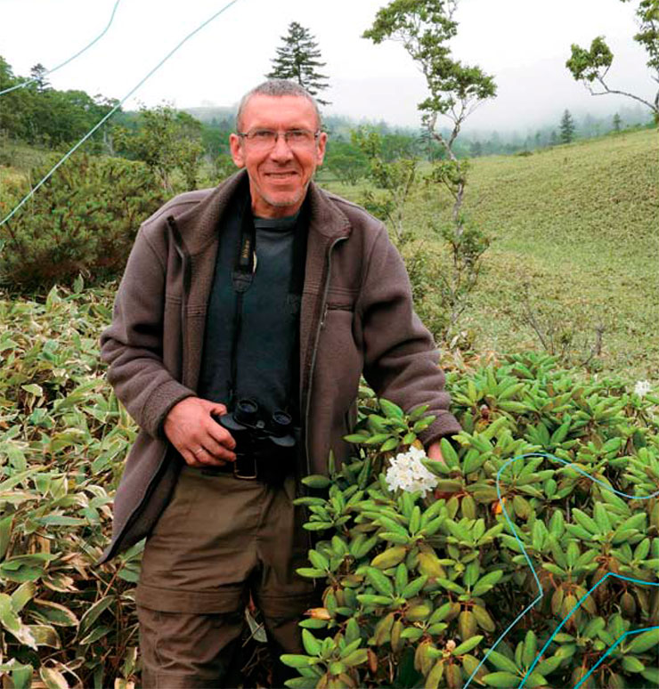 In July of 2018, the white flowers of the Kunashir rhododendron bloomed again. A. A. Kisleyko, the director of the nature reserve since 2015, is posing next to the rare plant